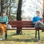 Two young people social distancing on park bench