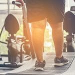 Obese man using treadmill in a gym