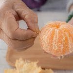 Elderly woman peeling an orange