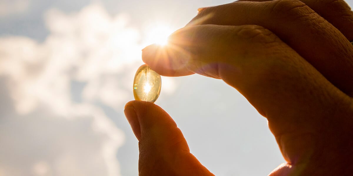 Vitamin d capsule being held up to sunlight